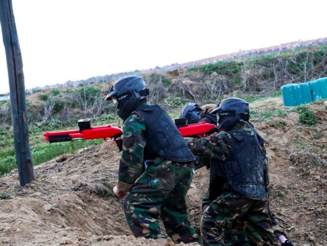  Kinder-Paintball-Spieler im Schützengraben 
