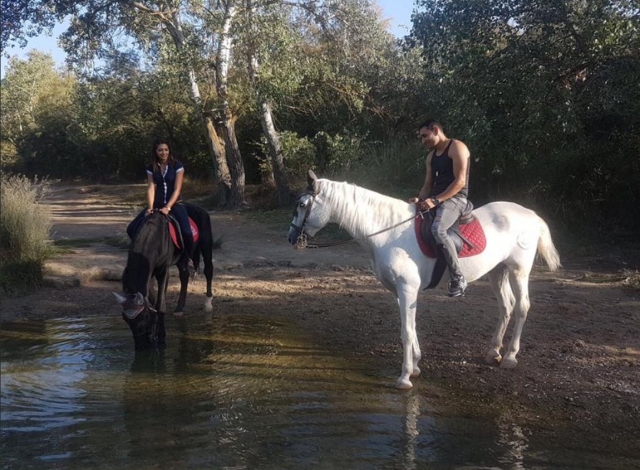 Pareja a caballo en el rio