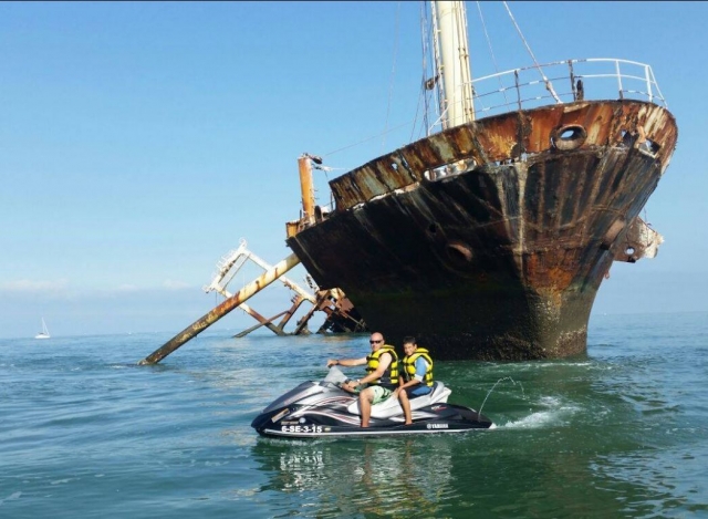 Pilotando la moto junto a los restos del barco
