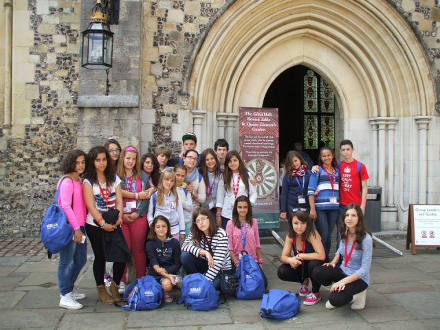 group of children with blue backpacks in front of a monument 