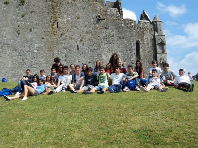  children sitting on the grass with a castle in the background 