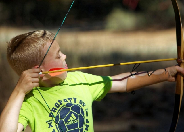 Peque tirando con arco en el campamento bilingue