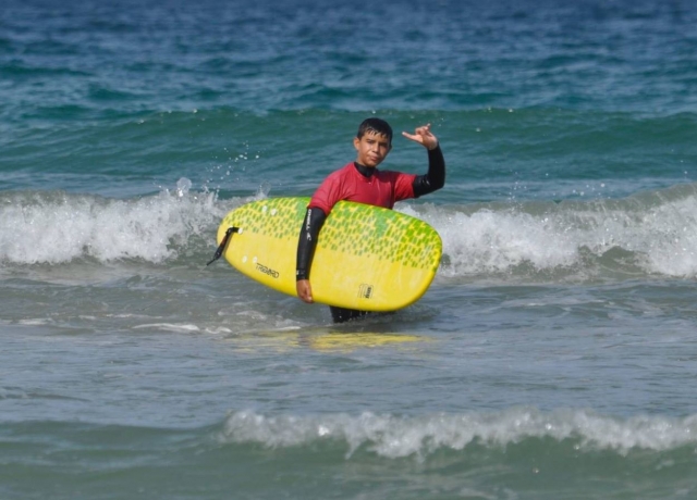 Alumno con tabla de surf amarilla