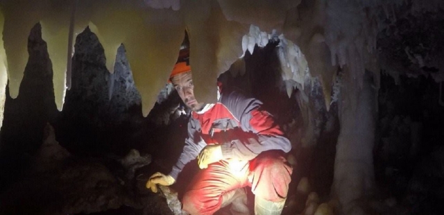 Explorador de cuevas tras estalagtita