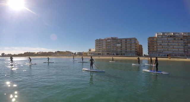 SUP con los edificios de Perelló de fondo