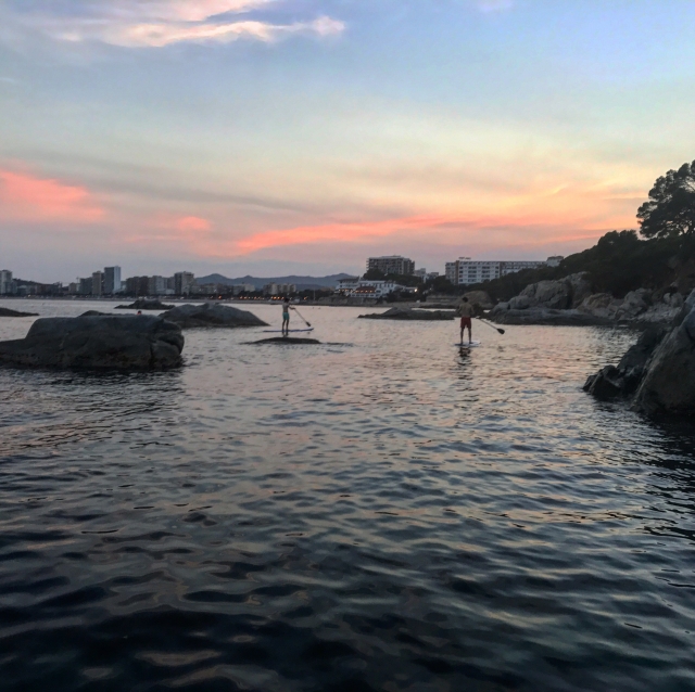  日落时划桨冲浪 