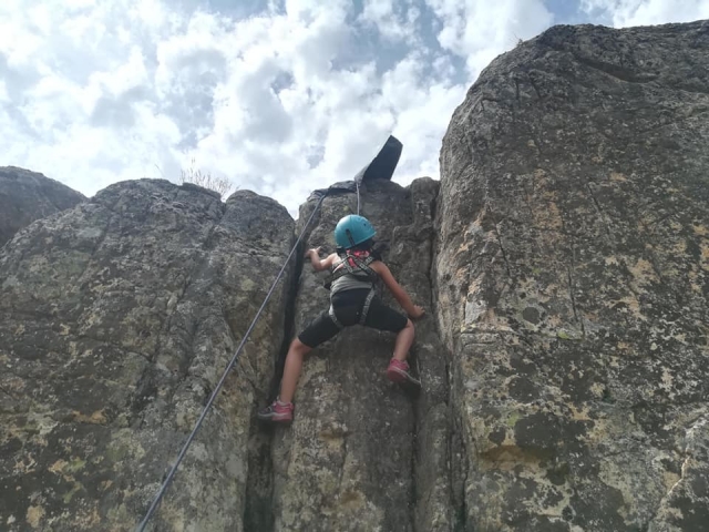 Joven escalando la pared rocosa