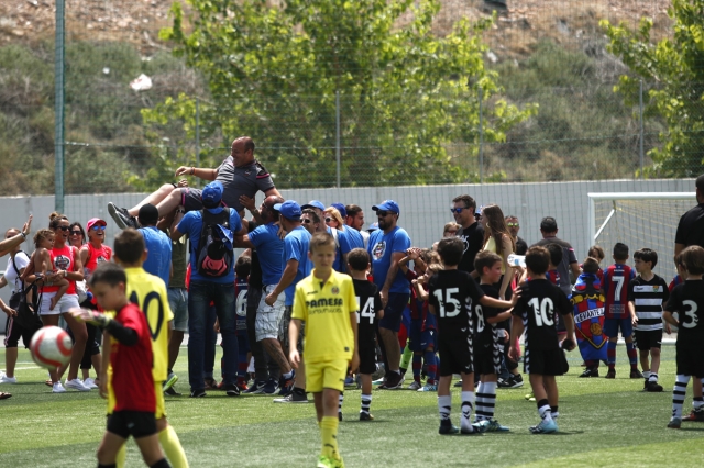 Pequeños jugadores de fútbol con el entrenador en alto