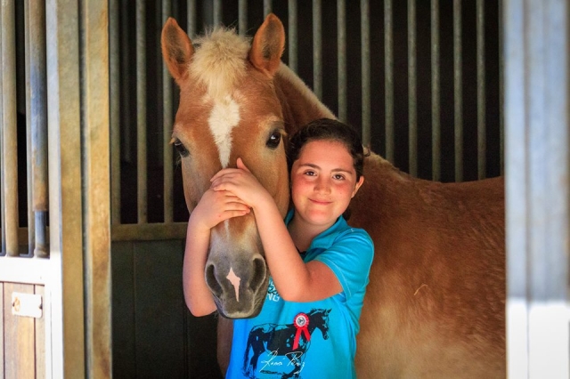  Girl next to the horse in the stable 