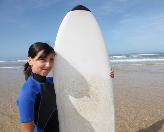 Alumna del campmento junto a la tabla de surf