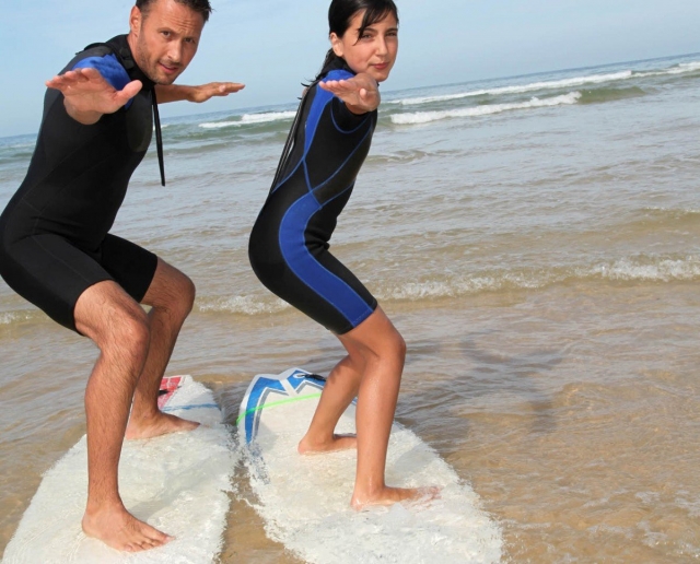 Alumna y monitor sobre las tablas de surf