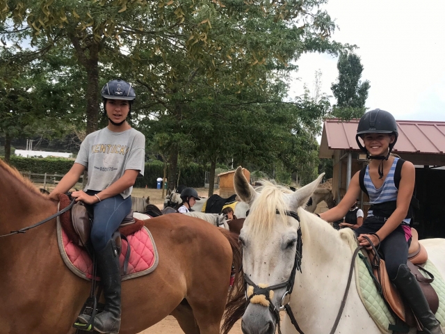 Amigas sobre los caballos en el campamento