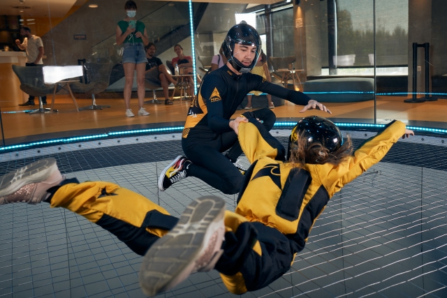 Instructor junto a la niña dentro del túnel de viento