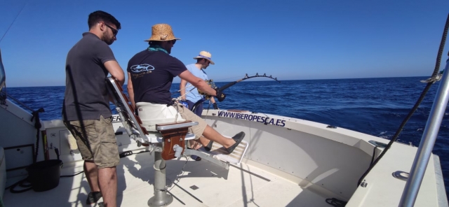 Dos usuarios pescando con caña mientras uno de ellos les observa
