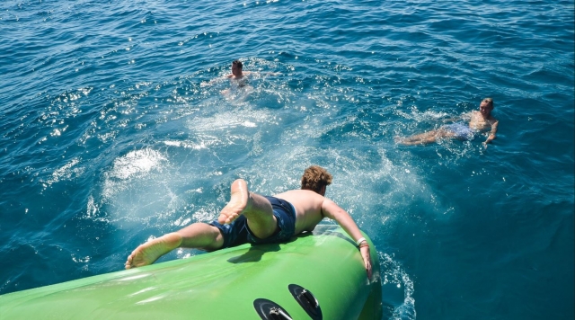  Ein Benutzer springt kopfüber ins Wasser und die schwimmende Rutsche hinunter, die nach draußen führt Unser Boot 