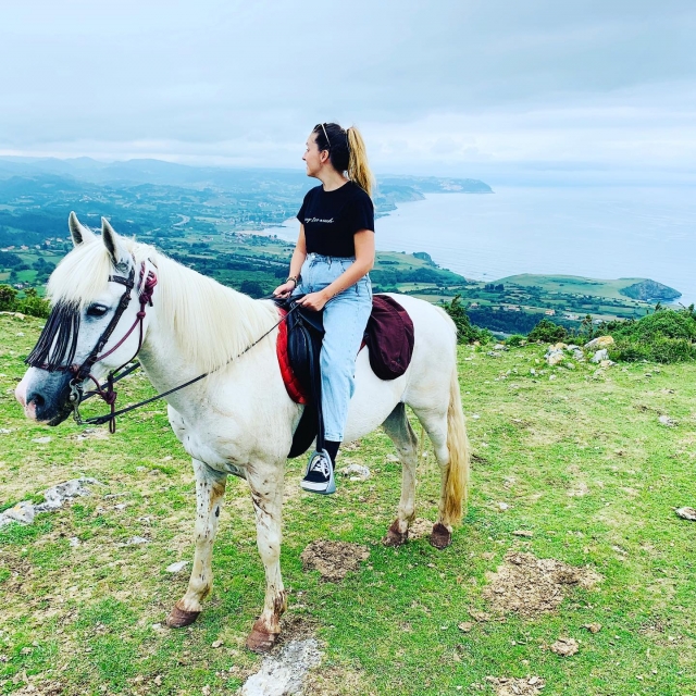 Una amazonas encima de un caballo blanco mira al horizonte 