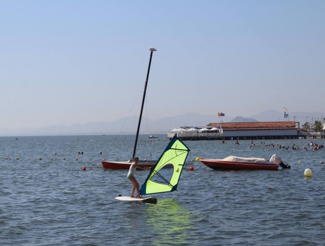 Étudiant en planche à voile soulevant la planche à voile 