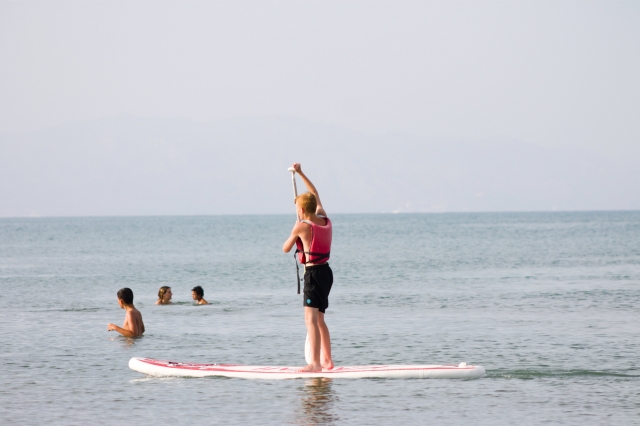 Em pé na prancha de paddle surf 