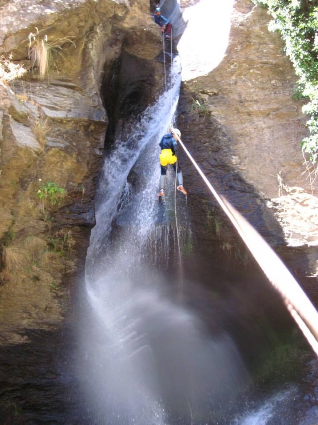 Practica la técnica del rápel durante un descenso de barranquismo 