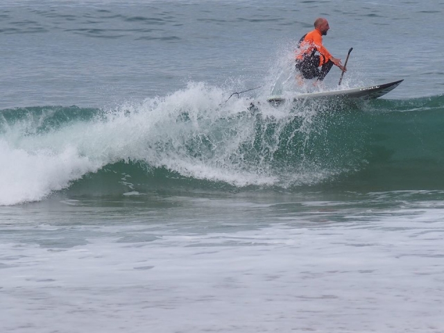  Surfer sur la vague avec la pagaie en main 