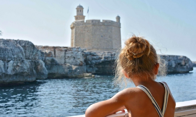 Niña a bordo navegando por Menorca