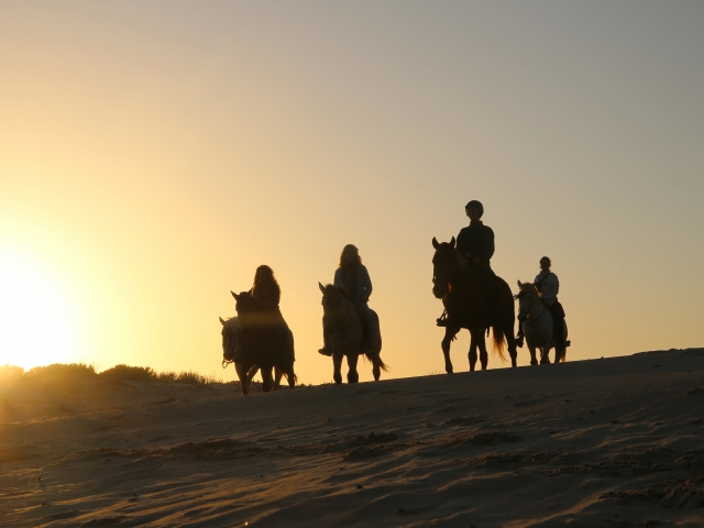 A caballo con la puesta de sol de fondo
