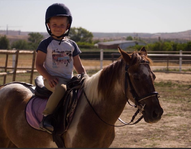 Pequeño aprendiendo a montar sobre el pony