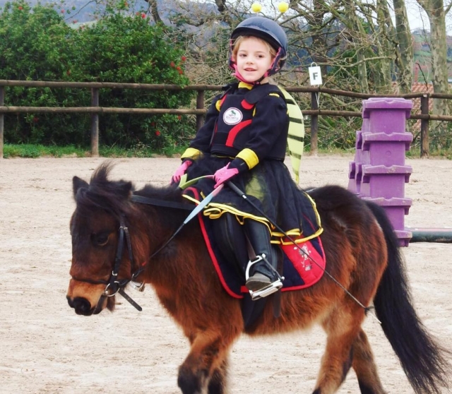  Kostümiertes Mädchen vergnügt sich mit ihrem Pony 