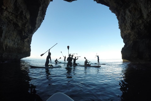  Diversi kayak che attraversano un gigantesco arco in pietra 