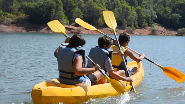 Un grupo de tres niños a bordo de un kayak triple