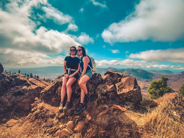 Una pareja de amigas posando en un saliente de roca