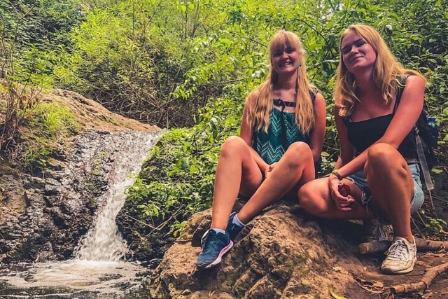  Um casal de amigos posa próximo a uma pequena cachoeira