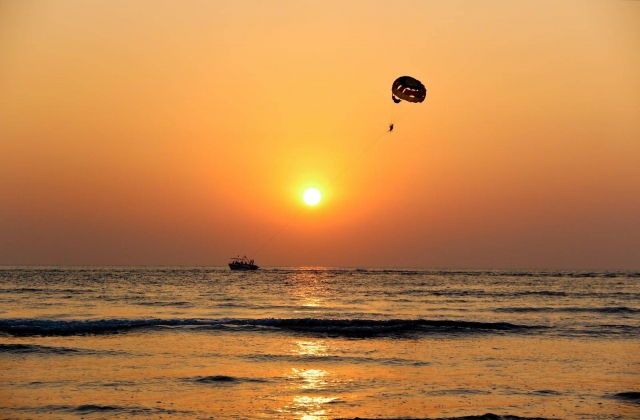 Una experiencia de parasailing con la puesta de sol de fondo
