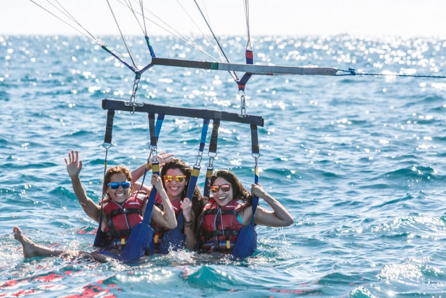  Un gruppo di tre amici a bagno nell'acqua dopo essere caduti durante il parapendio 