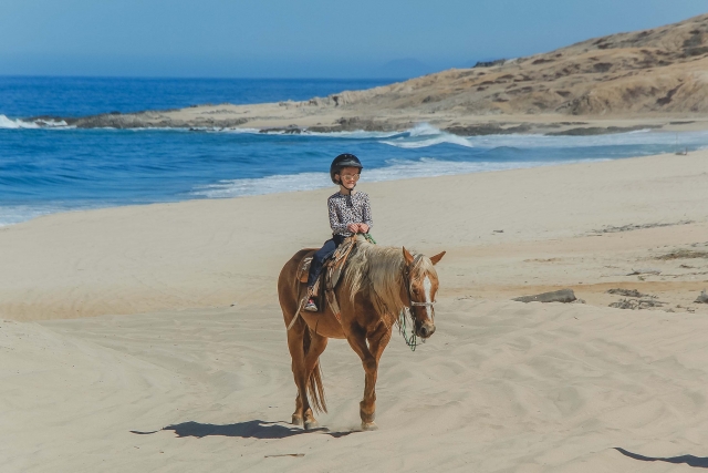 Niño en la playa a caballo