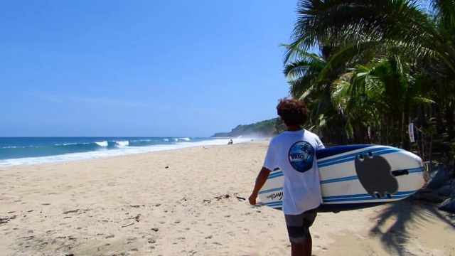 Caminando en la playa con tabla de surf