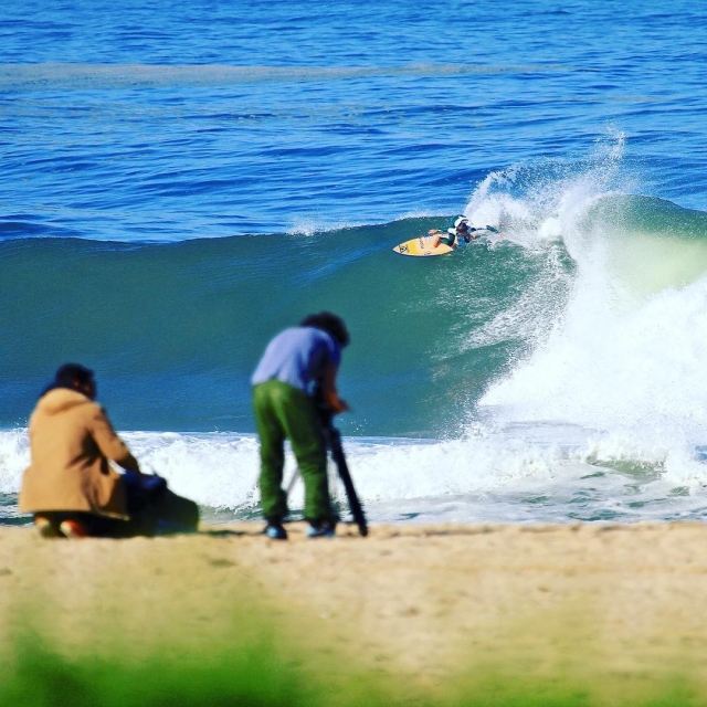  Ein paar Neugierige, die die Ausrüstung vorbereiten, um die Surfer zu fotografieren 