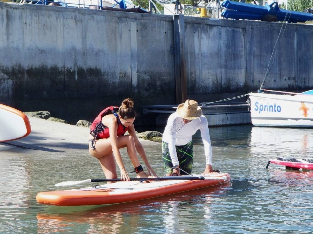  Hilft dem Mädchen, auf das SUP-Brett zu steigen 