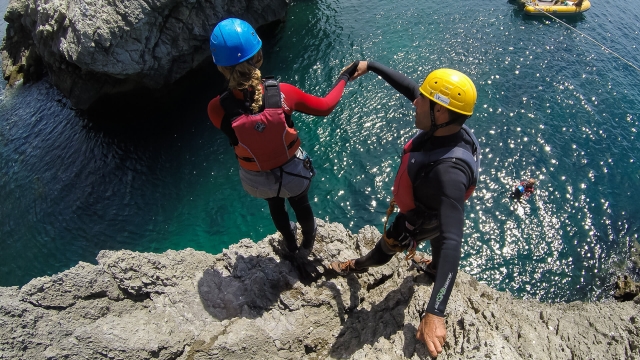  Ragazza che salta in acqua facendo coasteering 