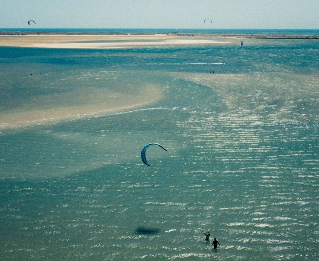 Instructor con el alumno de kitesurf de fondo