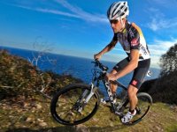 hombre montando en una mountain bike con el mar de fondo